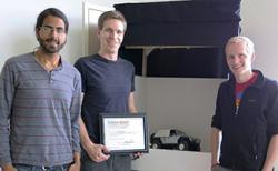 The Lumenous team (from left): Raj Sodhi, Kevin Karsch, and Brett Jones. They are standing in front of the display they used for the Cozad competition. Karsch is holding the certificate they received when they won the Cozad competition. 
