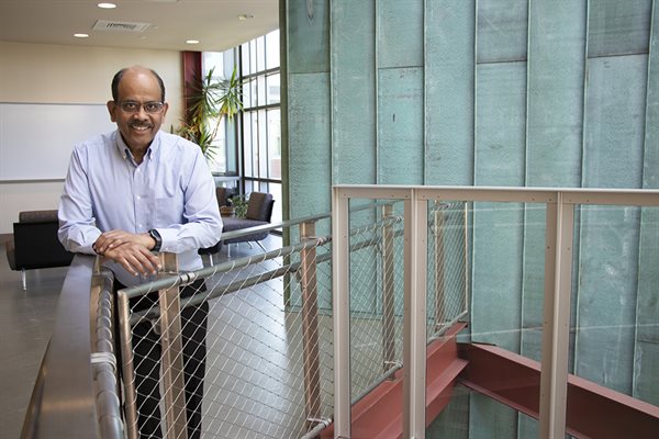 Illinois CS professor Sanjay Kale standing near a stairwell at the Thomas M. Siebel Center for Computer Science wearing a blue dress shirt.