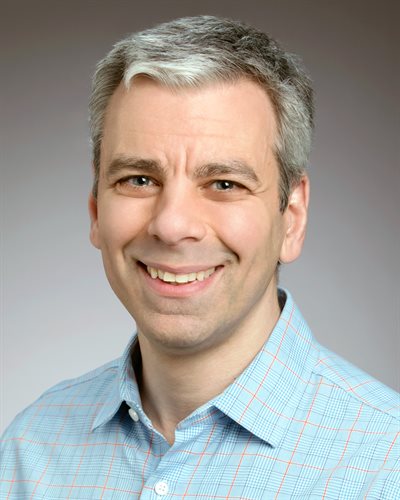 Illinois CS professor Paris Smaragdis headshot with a grey background and wearing a light blue shirt.