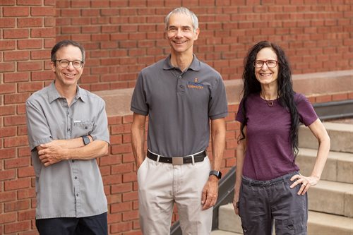 Illinois CS alumna Carla Scaletti, far right in a group photo with two other people - outside and in front of a brick building.