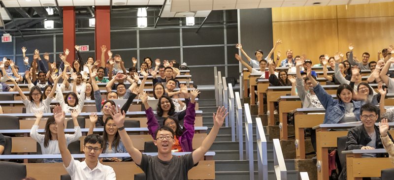 Classroom at the Thomas M. Siebel Center for Computer Science full of students, raising their hands in celebration.