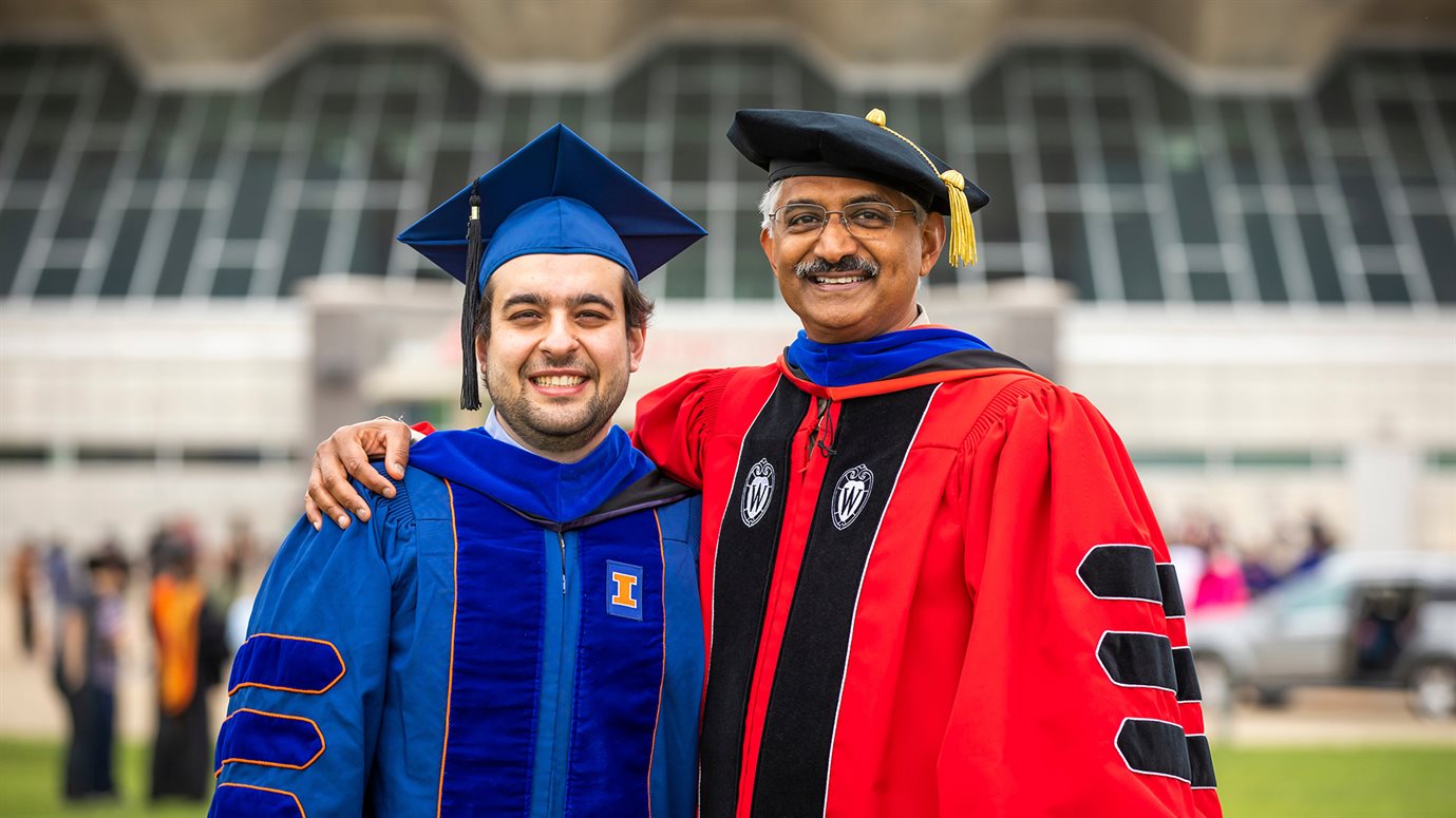 Professor Vikram Adve with a student at graduation in front of State Farm Center.