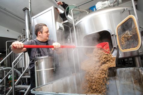 Darin Riggs BS CS '03) removes spent grain from the brewhouse at Riggs Brewery in Urbana. (photo by L. Brian Stauffer)